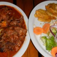 Typical meal in Haiti consisting of goat in Kreyol sauce, fried plantains, and salad